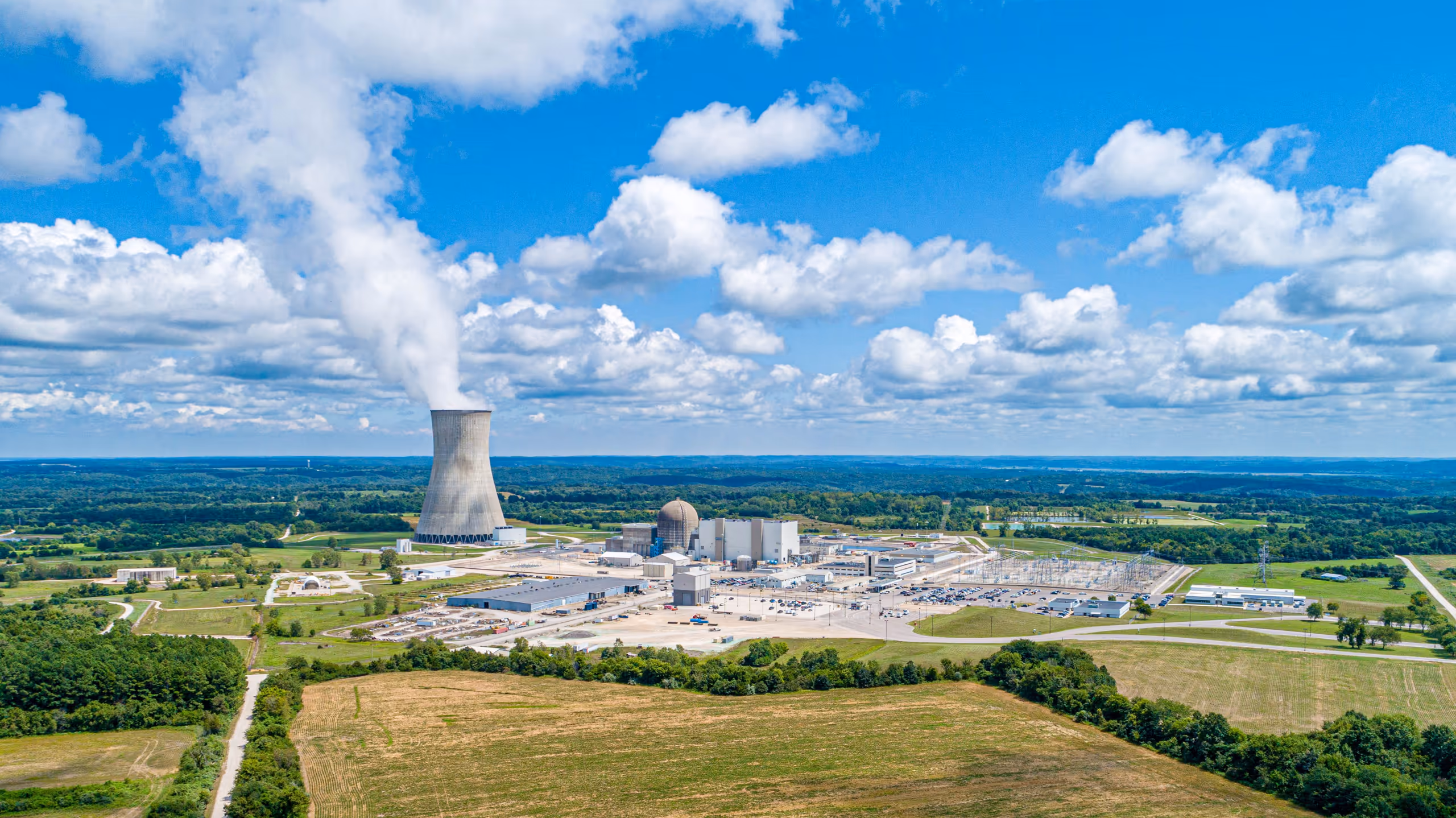 Aerial view of a nuclear power plant with its cooling tower under a bright sky